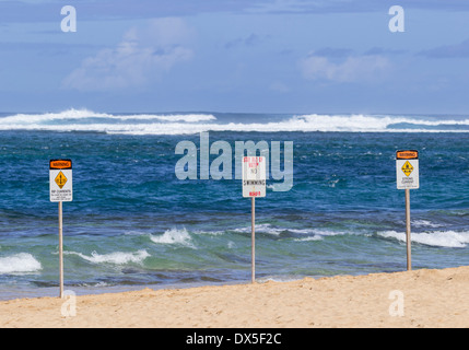 Three warning signs on a beach in Hawaii - no swimming and strong currents in treacherous winter waters Stock Photo