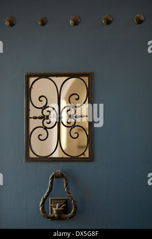 Iron door knocker and window detail on blue Spanish front door Stock Photo