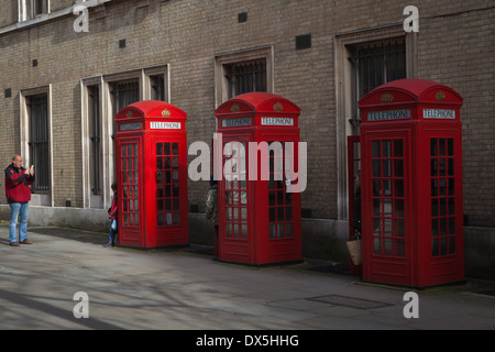 3 red telephone boxes with family posing for a photograph Stock Photo