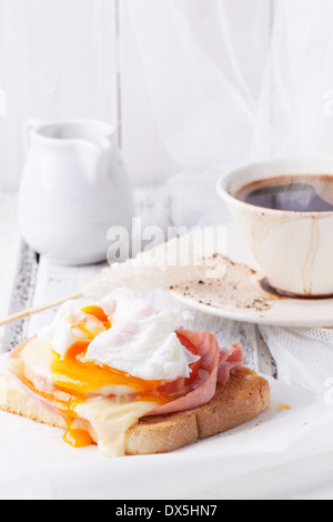 Breakfast with cup of coffee and toast with cheese and poached egg served on white wooden table Stock Photo