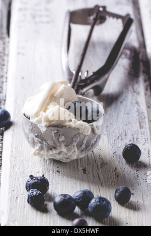 Ice cream in metal spoon with blueberries on white wooden table Stock Photo