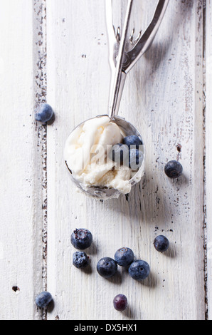 Top view on metal spoon of vanilla ice cream with blueberries on white wooden table Stock Photo