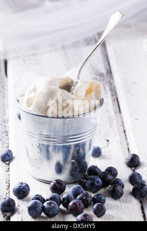 Ice cream, served in little metal pail with blueberries on white wooden table Stock Photo