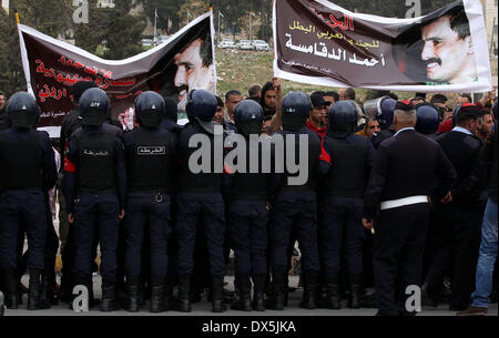 Amman, Amman. 18th Mar, 2014. Riot police stand guard as activists and relatives of Ahmed Daqamseh, a Jordanian soldier who was sentenced to life imprisonment for shooting dead seven Israeli school girls in the Jordanian town of Baqura in March 1997, shout slogans against Israel and Jordan's government during a protest to demand his release, in front of parliament in Amman, March 18, 2014. Credit:  Mohammad Abu Ghosh/Xinhua/Alamy Live News Stock Photo