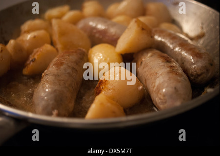 Sausages and potatoes cooking in a frying pan Stock Photo