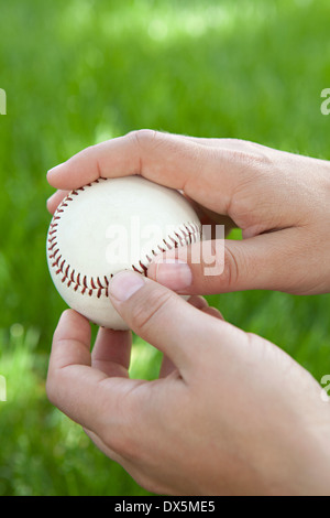 Man's hands holding baseball in grass, close up Stock Photo