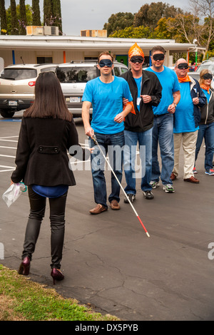 Visitors to a school for the blind in Tustin, CA, are blindfolded to allow them to experience sightlessness as they learn to use a white cane for walking in a parking lot. Stock Photo