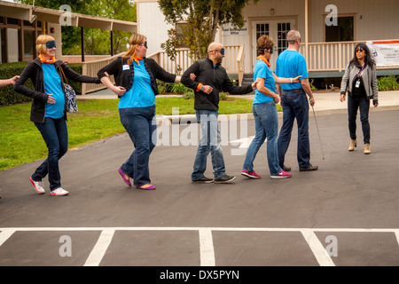 Visitors to a school for the blind in Tustin, CA, are blindfolded to allow them to experience sightlessness as they learn to use a white cane for walking in a parking lot. Stock Photo