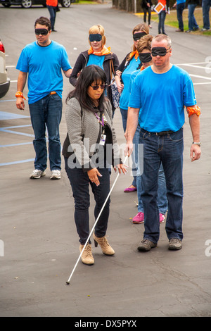 Visitors to a school for the blind in Tustin, CA, are blindfolded to allow them to experience sightlessness as they learn to use a white cane for walking in a parking lot. Stock Photo