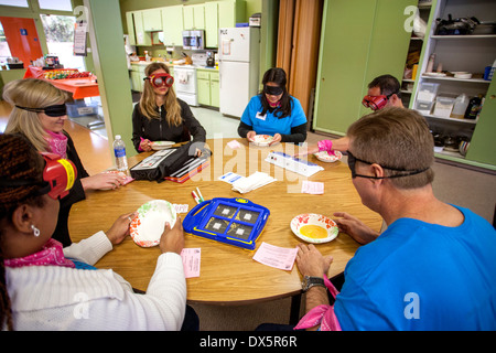 Visitors to a school for the blind in Tustin, CA, are blindfolded to allow them to experience sightlessness as they are served lunch. Device on the table is a speech annunciator. They are also not allowed to speak. Stock Photo