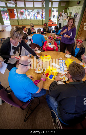 Visitors to a school for the blind in Tustin, CA, are blindfolded to allow them to experience sightlessness as they are served lunch. Device on the table is a speech annunciator. They are also not allowed to speak. Stock Photo