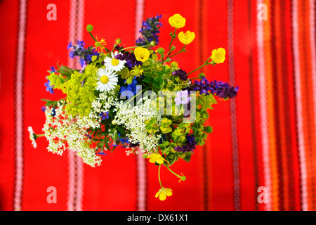 Wild flower bunch shot from above with a red decorated table cloth in the background. Stock Photo