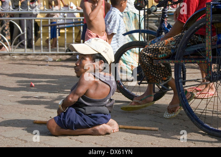 A handicapped man is sitting on the ground near a disabled person confined to a wheelchair in Phnom Penh, Cambodia. Stock Photo