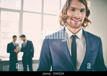 Closeup portrait of a young businessman smiling and posing at camera on the foreground Stock Photo