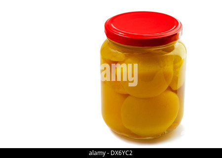 Slices of canned peaches in syrup in a glass jar. Presented on a white background. Stock Photo