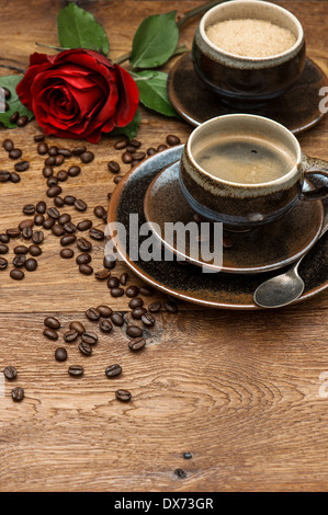 Cup of black coffee and red rose flower on wooden background. Festive arrangement Stock Photo