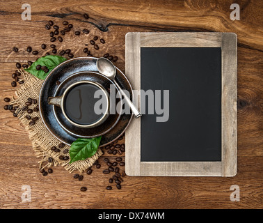 cup of coffee and antique blackboard. coffee leaves and beans. top view. selective focus Stock Photo