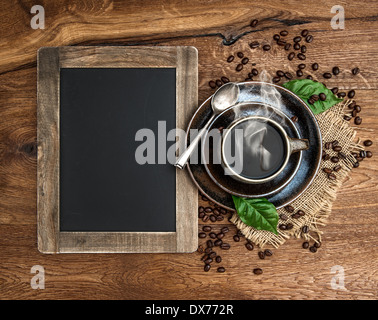 cup of coffee and antique blackboard. coffee leaves and beans. top view. selective focus Stock Photo