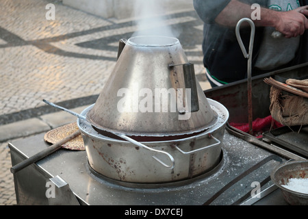 A metal cart stall holder roasting chestnuts on the streets of Lisbon, (Lisboa), Portugal. Stock Photo