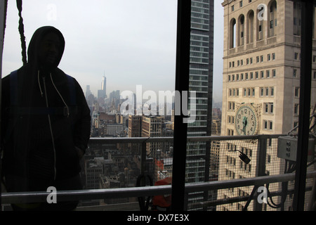 Inside view of a window washer in silhouette wearing a hoodie while standing on scaffolding at a New York City skyscraper Stock Photo