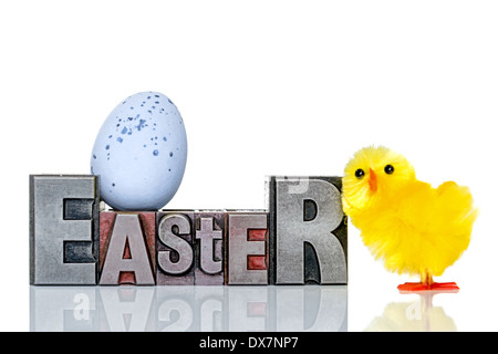 The word Easter in old metal letterpress with a toy chick and candy covered chocolate egg, isolated on a white background. Stock Photo