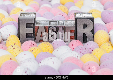 The word Easter in old metal letterpress surrounded by candy covered mini chocolate eggs. Stock Photo