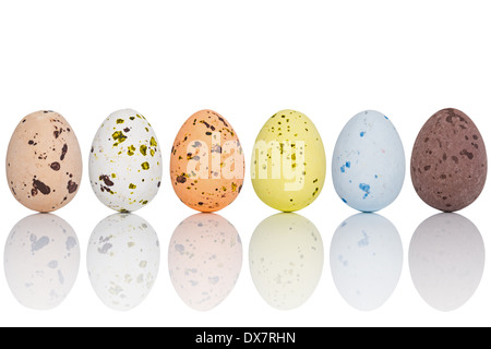 Six candy coated chocolate Easter eggs in a line, isolated on white with clipping path. Stock Photo