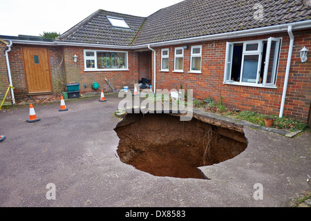 General view of a 30 ft deep sinkhole, with a car at the bottom, outside a family house in Walter's Ash, near High Wycombe Stock Photo
