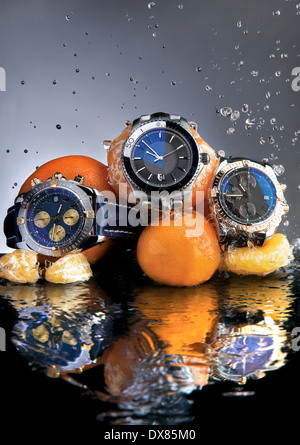 Designer watches with mandarins on water surface. Stock Photo