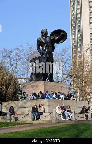 People sitting by the Wellington Memorial with the giant statue of Achilles in Hyde Park, London, England, United Kingdom. Stock Photo