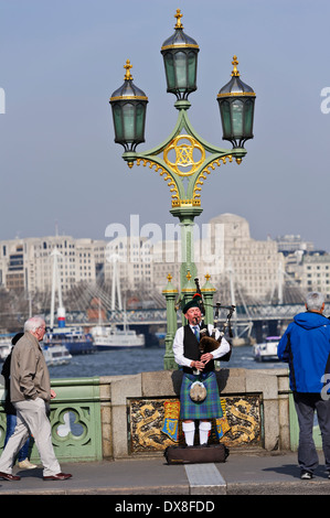 Scottish bagpiper playing music with bagpipe on Westminster bridge, London, England, United Kingdom. Stock Photo