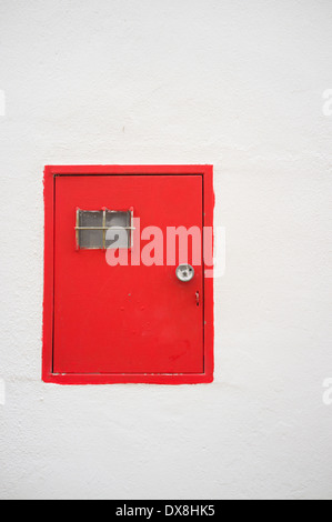 Red electricity meter door on a whitewashed Andalusian facade Stock Photo