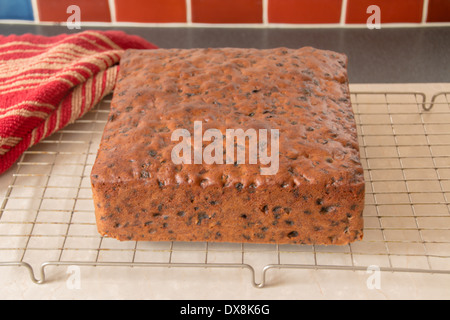 rich traditional fruit cake removed from baking tin, square cake ready to ice placed on wire cooling rack (4 0f a series of 8) Stock Photo