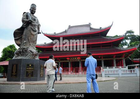 Semarang, Indonesia. 20th Mar, 2014. Tourist stand beside the statue of Chinese navy explorer Zheng He in front of the Sam Poo Kong Temple, in Semarang, Central Java, Indonesia, March 20, 2014. Chinese navy explorer Zheng He who visited the Central Java Province's port city of Semarang 600 years ago, built a mosque and set up a Chinese Muslim community in the city. The mosque was later turned into a temple by Semarang residents, now known as Sam Poo Kong with a huge Zheng He statue in its front. © Zulkarnain/Xinhua/Alamy Live News Stock Photo