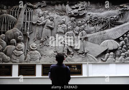 Semarang, Indonesia. 20th Mar, 2014. A tourist looks at a relief wall telling the story of Chinese navy explorer Zheng He in front of the Sam Poo Kong Temple, in Semarang, Central Java, Indonesia, March 20, 2014. Chinese navy explorer Zheng He who visited the Central Java Province's port city of Semarang 600 years ago, built a mosque and set up a Chinese Muslim community in the city. The mosque was later turned into a temple by Semarang residents, now known as Sam Poo Kong with a huge Zheng He statue in its front. © Zulkarnain/Xinhua/Alamy Live News Stock Photo