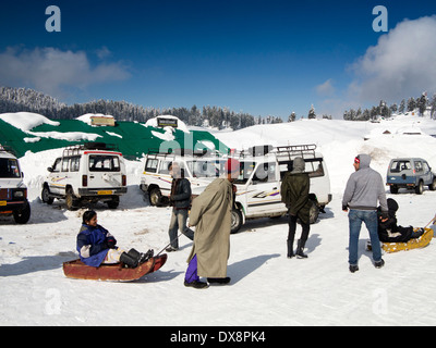 India, Kashmir, Gulmarg, Himalayan Ski Resort, men pulling tourists on toboggans in snow Stock Photo
