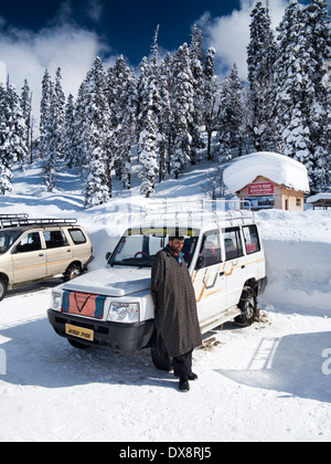 India, Kashmir, Gulmarg, Himalayan Ski Resort main bazaar, driver and share taxi with chains on wheels in snow Stock Photo