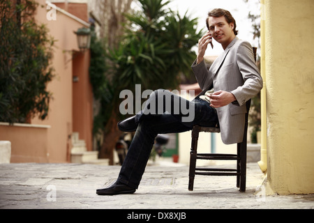Businessman sitting outside on the cell phone Stock Photo