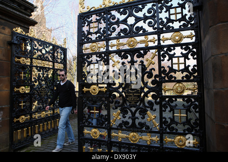 Man walking through the elaborate main gates to the Necropolis in Glasgow Stock Photo