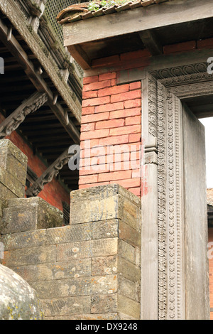 Carved wood door jambs and lintel on the red brick wall surrounding the Kalika Mandir of the Gorkha Durbar-Gorkha district-Nepal Stock Photo