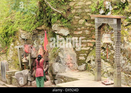 Hindu faithful woman prays to a Lord Hanuman's statue at the entrance to the Gorakhnath cave-temple. Gorkha Durbar-Nepal. Stock Photo