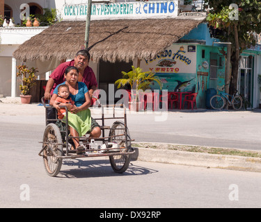 Family Transportation: tricycle. A multigenerational family rides down the main highway through Tulum. Stock Photo