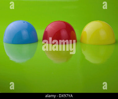 Three half shell plastic Easter egg shells, on a glossy green background, with reflection, Stock Photo