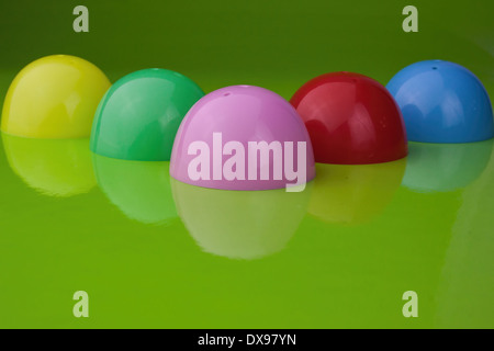 Five half shell plastic Easter egg shells, on a glossy green background, with reflection, Stock Photo