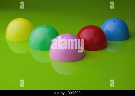 Five half shell plastic Easter egg shells, on a glossy green background, with reflection, Stock Photo