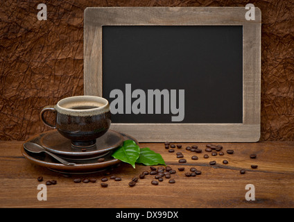 cup of coffee and antique blackboard. coffee leaves and beans. retro style image Stock Photo
