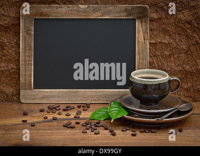 cup of coffee and antique blackboard for your text. coffee leaves and beans Stock Photo