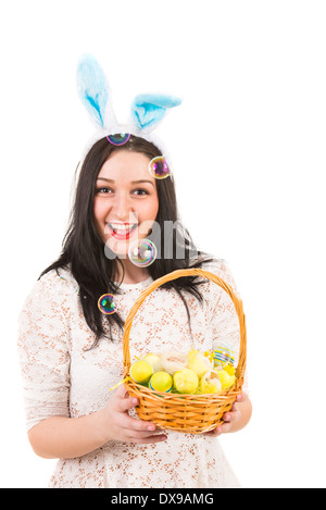 Cheerful woman with bunny ears holding Easter basket and bubbles of soap are blowing out Stock Photo