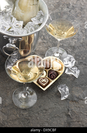 two glasses, bottle of champagne and chocolate pralines box in heart shape. selective focus Stock Photo