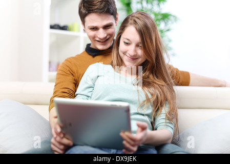 Young couple using digital tablet indoors on the sofa Stock Photo